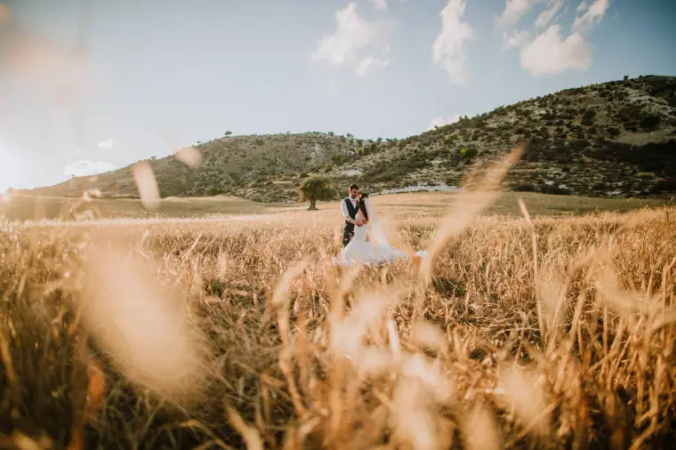 Claire and Sean as small figures in a vast golden field below the hills
