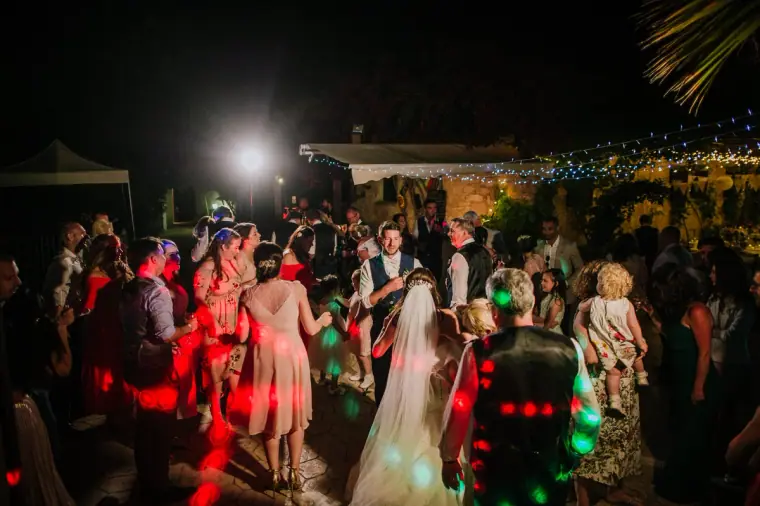 Guests and the bride dancing under coloured disco lights