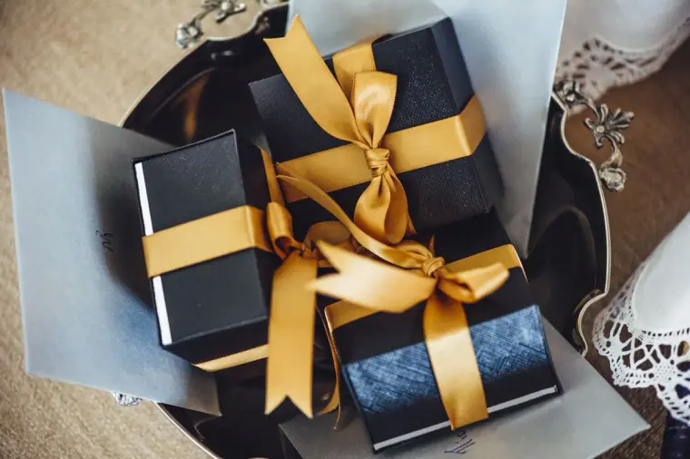 Navy gift boxes tied with gold satin ribbon on a tray