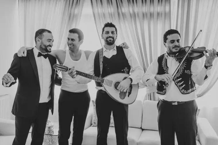 Black-and-white photo of traditional musicians playing for the groom and his friend