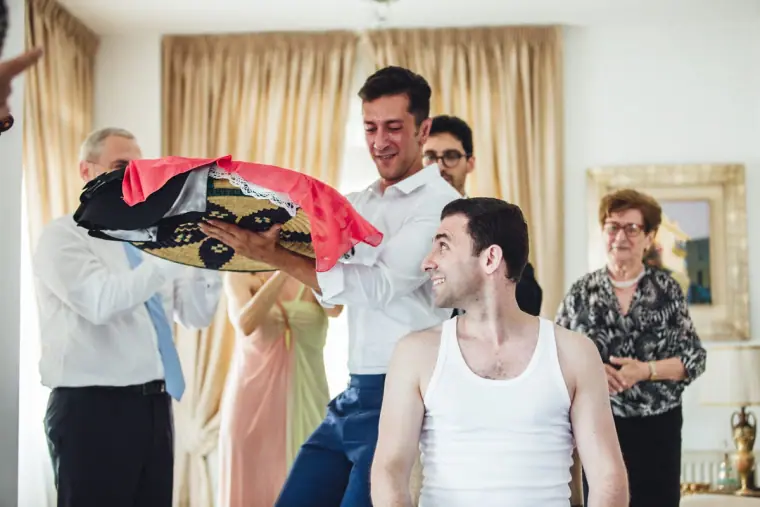 Family member waving a red scarf over Angelos during the Cypriot dressing ritual