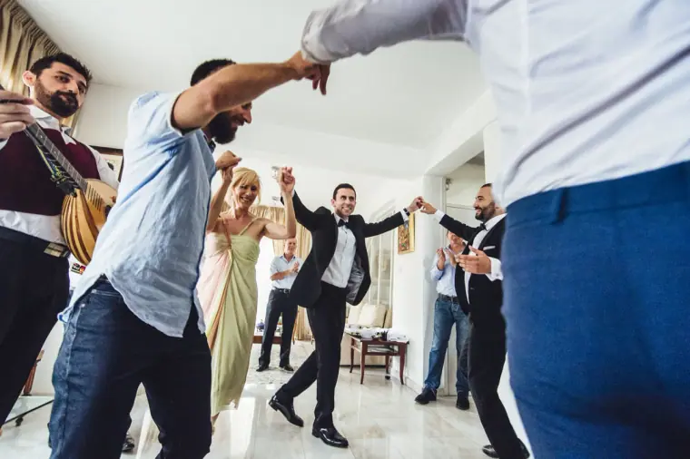 Guests dancing in a circle with the groom as the musicians play