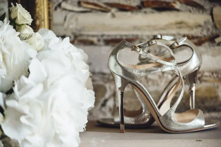Strappy silver bridal heels beside white flowers