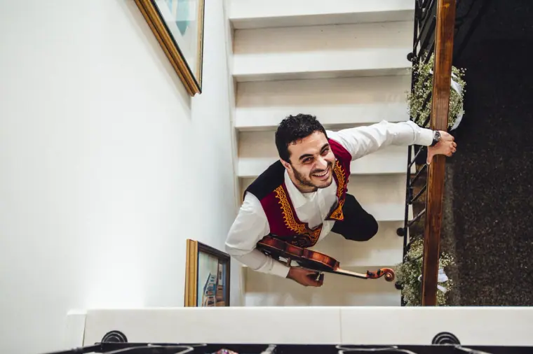 Violinist in a traditional waistcoat playing at the foot of the stairs