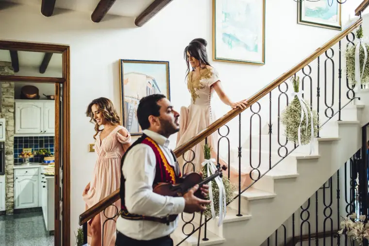 Bridesmaids coming down the staircase as the musician plays
