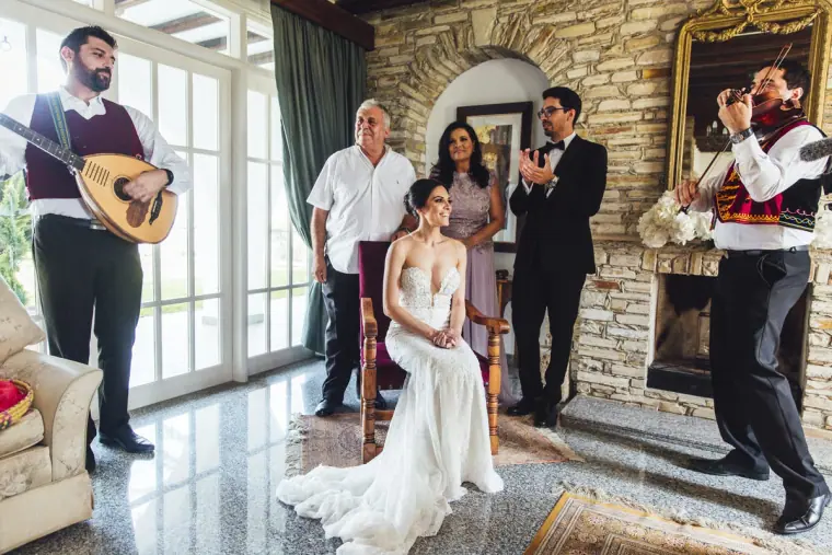 Ruby seated in her gown as musicians play for the Cypriot bride's dressing