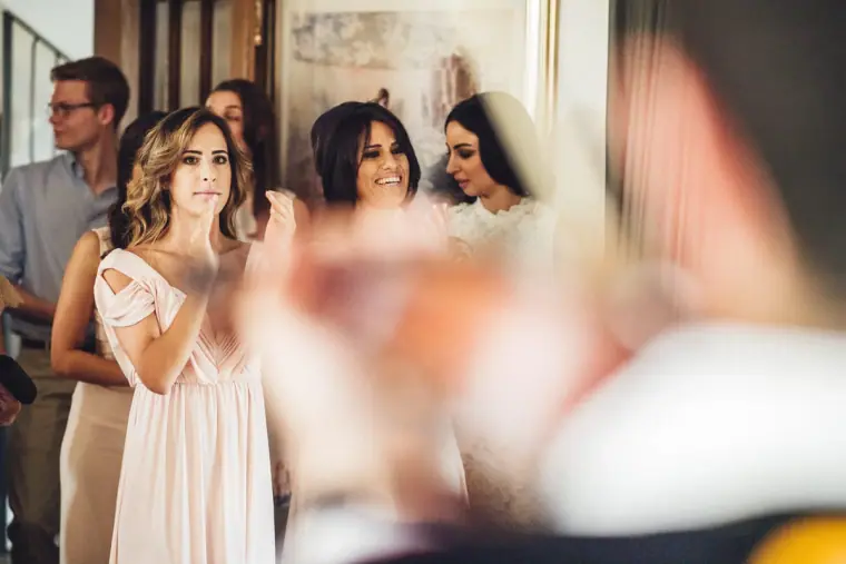 Bridesmaids and family smiling as they watch the bride's dressing