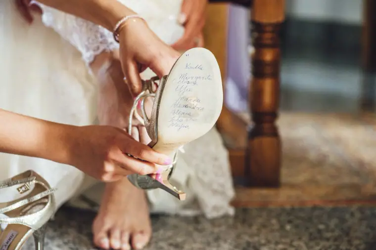 Bridesmaid fitting a bridal shoe with handwritten names on the sole