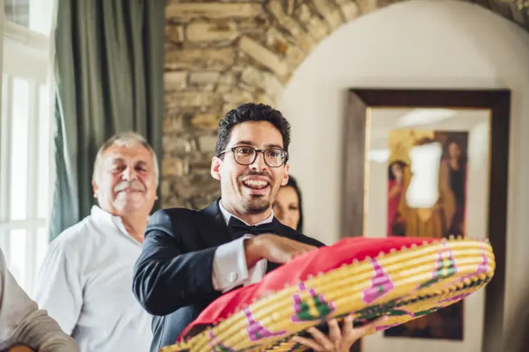 Smiling guest holding a colourful woven tray during the bride's dressing