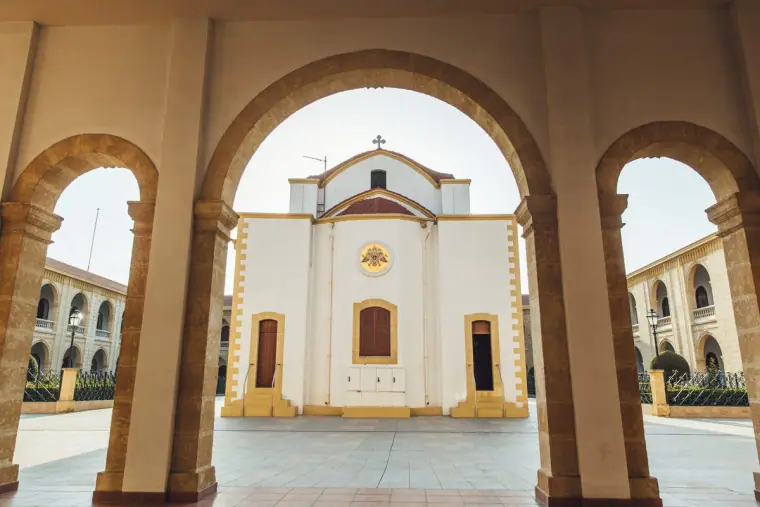 White church façade framed by a colonnade of stone arches