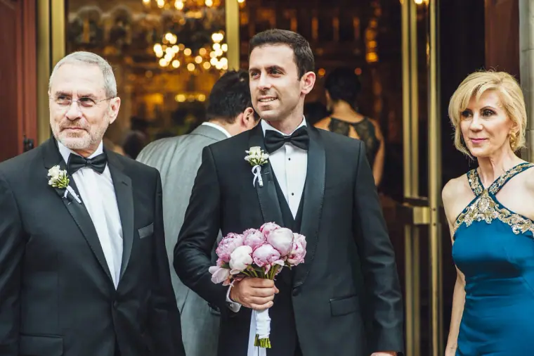 Angelos holding a pink peony bouquet beside his best man at the church door