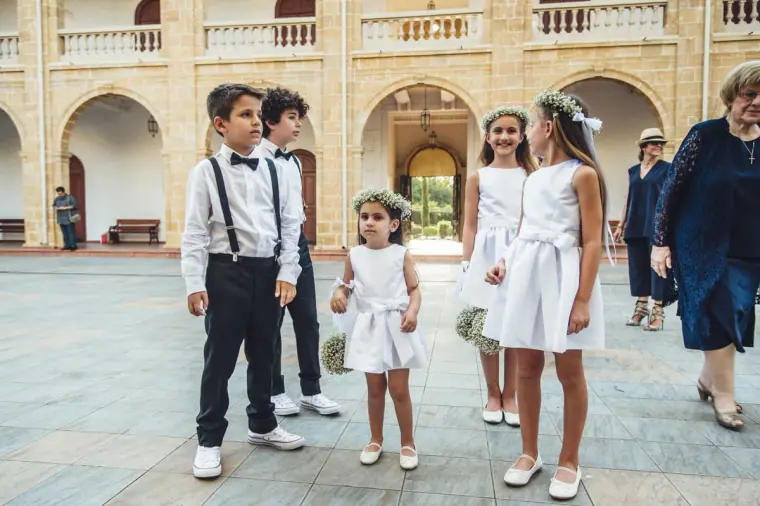 Page boys and flower girls waiting in a sunny arcaded courtyard