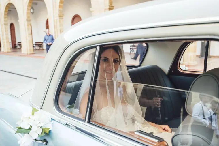 Ruby in her veil looking out from the classic wedding car