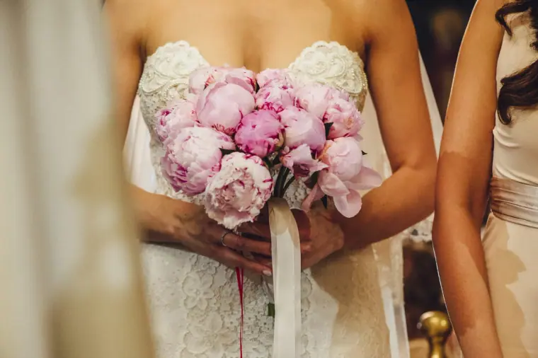 Close-up of Ruby's pink peony bouquet held against her lace gown