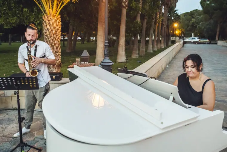 Saxophonist and pianist at a white grand piano playing the garden drinks reception
