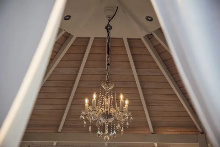 Crystal chandelier hanging inside a white wooden gazebo ceiling