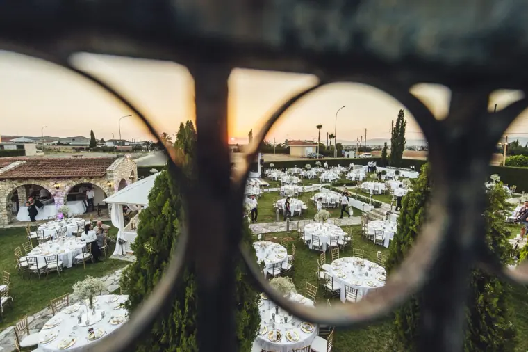 Reception lawn of white-clothed tables seen through a wrought-iron gate