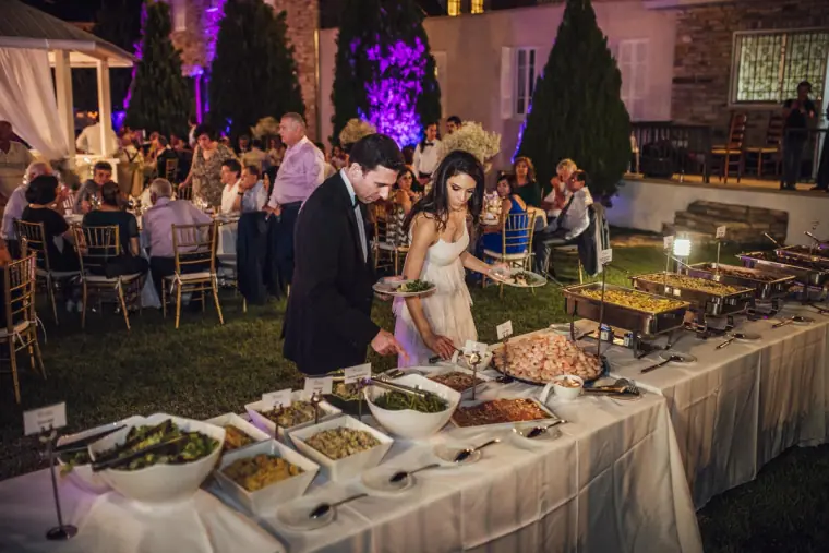 Bride and groom at a lantern-lit buffet table in the evening garden