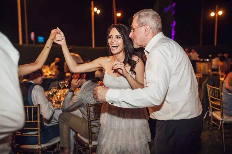 Bride dancing with an older guest, hands raised, at the evening reception