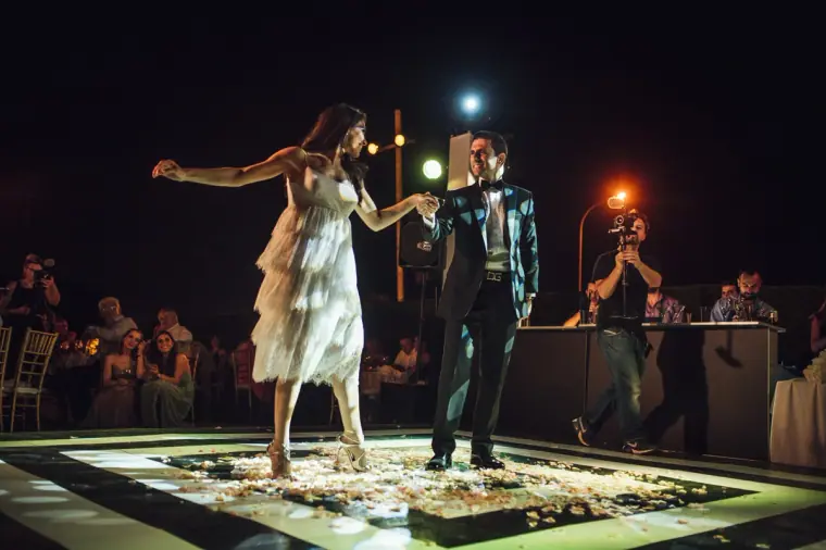 Ruby and Angelos dancing their first dance on an illuminated floor at night