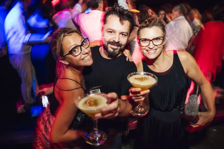 Three guests holding espresso martinis and smiling on the dance floor