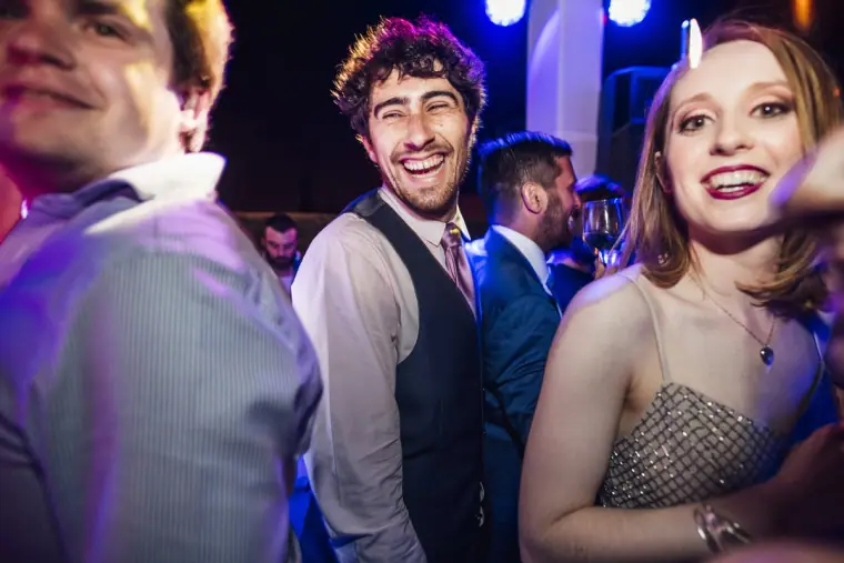 Guests beaming for the camera on the dance floor under blue light