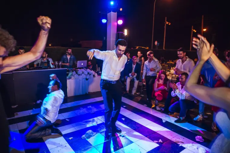 Guest dropping to his knees mid-dance on the lit floor as others cheer