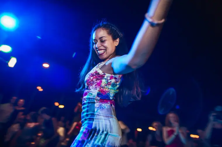 Guest in a colourful floral dress dancing under blue stage lights