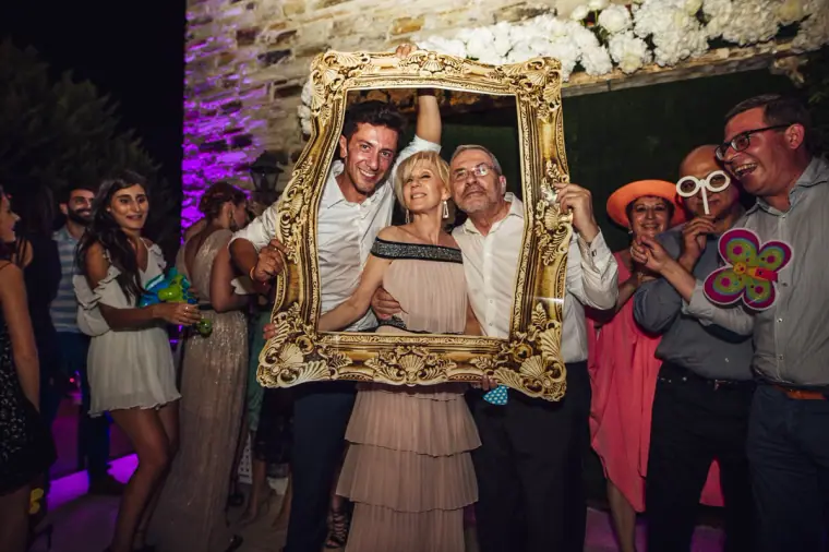 Guests posing inside an ornate gold photo-booth frame with props