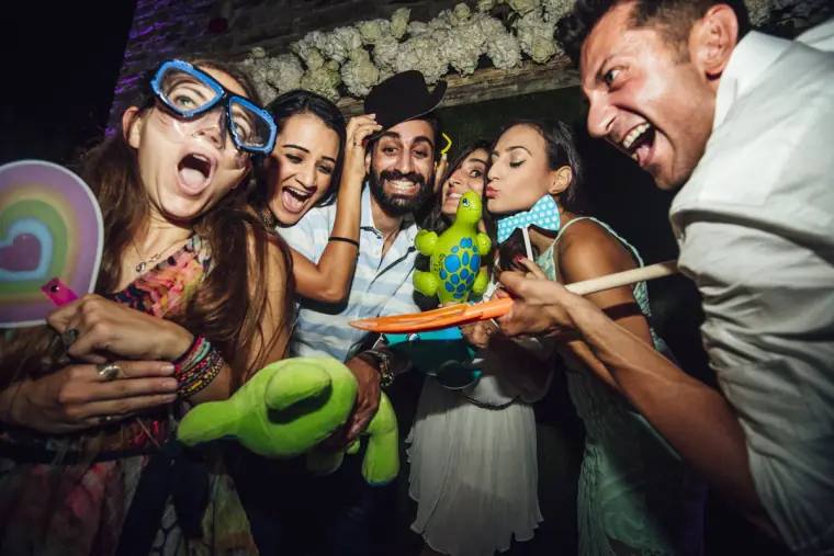Guests pulling funny faces with inflatable props and goggles at the photo booth