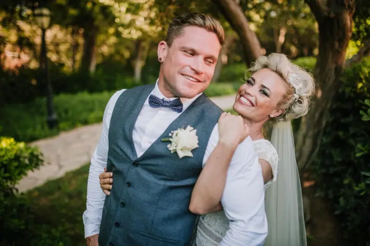 Laughing bride hugging her groom from behind under garden trees at Elysium, Paphos