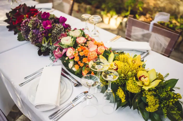 Top table with a lush garland of red, orange and yellow flowers at Vasilias Nikoklis Inn