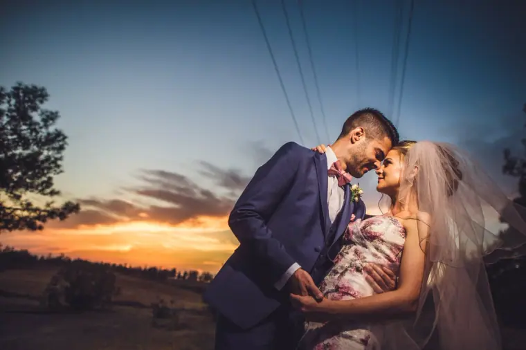 Groom holding the bride close against a vivid sunset sky at Vasilias Nikoklis Inn