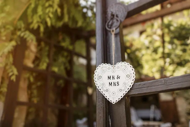 Wooden "Mr & Mrs" heart hanging from a gate post among vines