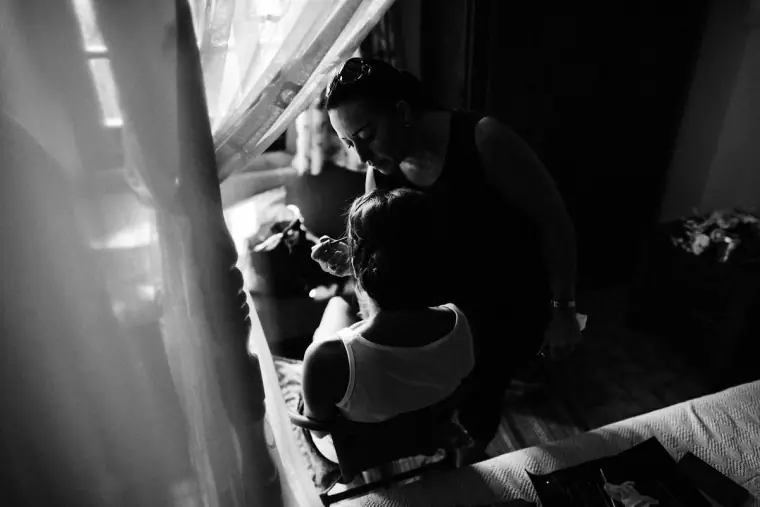 Black-and-white photo of the bride's hair being styled by the window