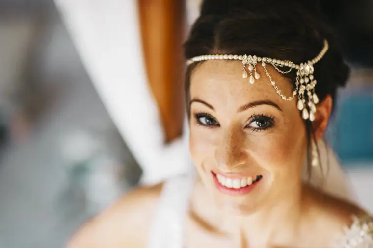 Bride smiling up at the camera wearing a crystal-and-pearl headpiece