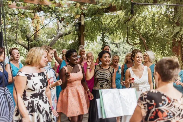 Guests cheering and smiling as the bride walks among them after the ceremony