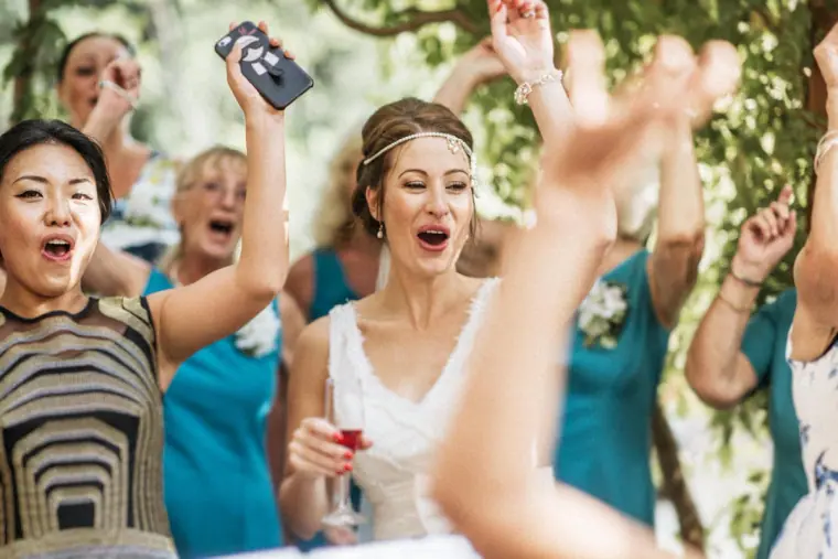Bride and guests cheering with raised arms under the pergola at Vasilias Nikoklis Inn