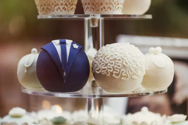 Cake pops decorated as a groom's suit and a lace bride's dress on a glass stand