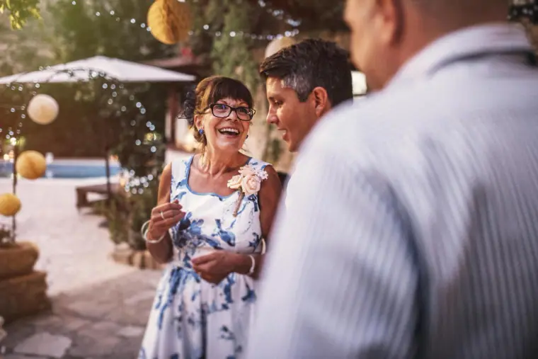 Laughing guest in a floral dress chatting at the evening reception by the pool