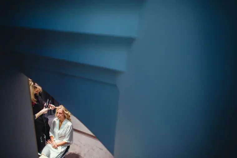 Bridesmaid seated on the stairs, seen through a blue-toned stairwell