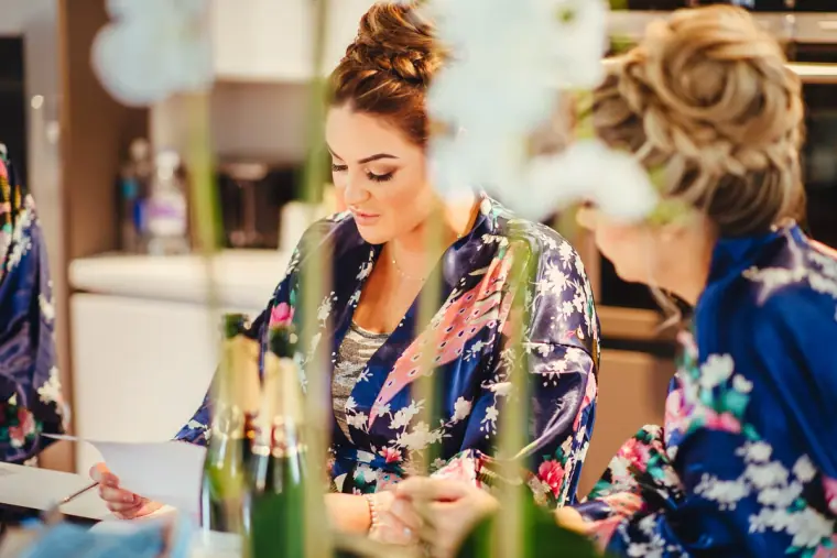 Leonnie in a floral robe sharing a moment with a bridesmaid during preparations
