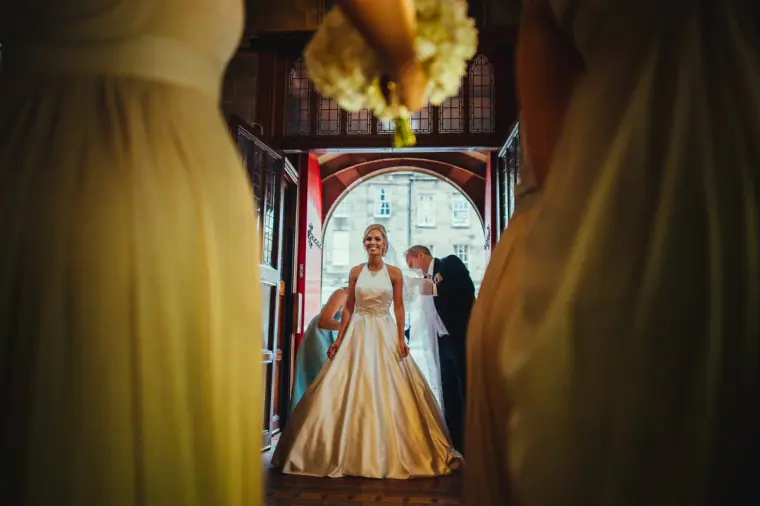 Bride arriving through a doorway, framed between two bridesmaids