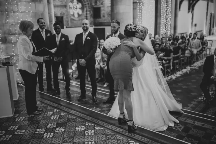 Black-and-white photo of the bride hugging a guest during the ceremony
