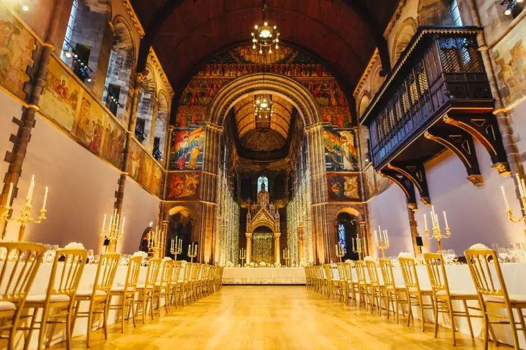 Long banquet tables with gold chairs stretching beneath the murals of Mansfield Traquair