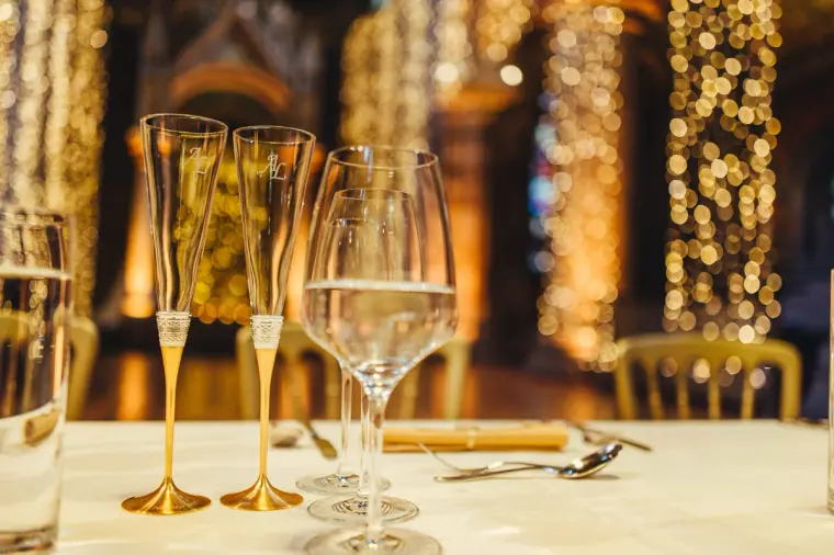 Gold-stemmed champagne flutes and wine glasses on a white tablecloth