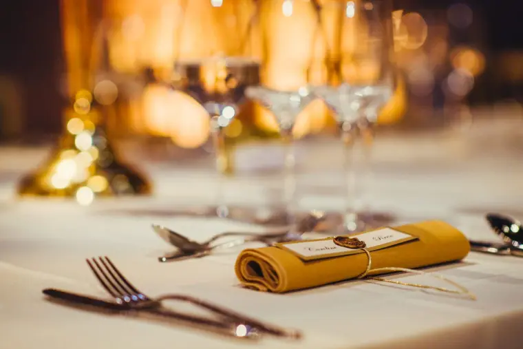 Gold napkin and place name tied with twine on a reception place setting