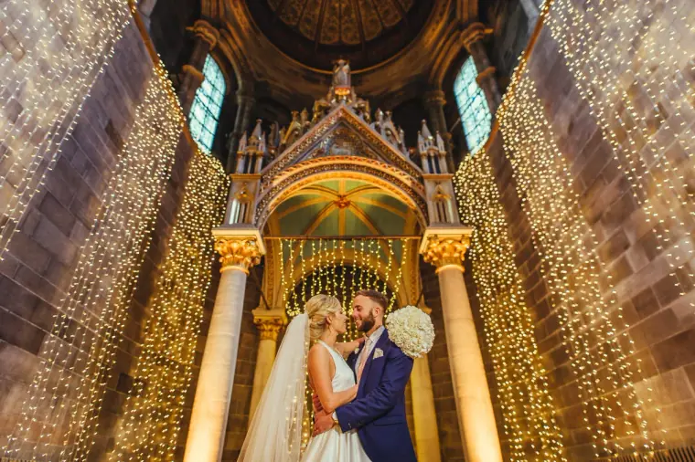 Couple kissing under the illuminated canopy and soaring arches of Mansfield Traquair