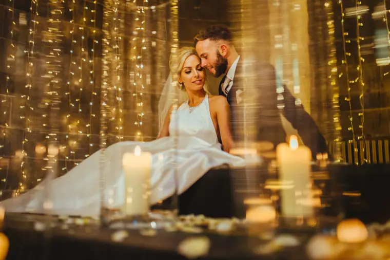 Leonnie and Andy embracing among candles and curtains of fairy lights at Mansfield Traquair, Edinburgh