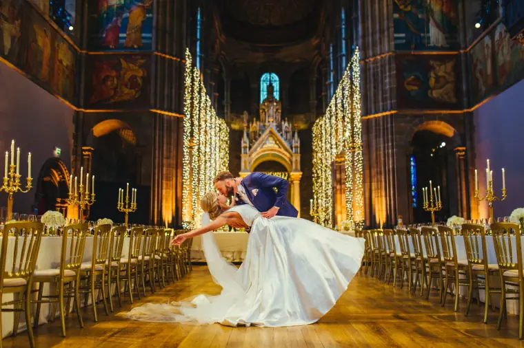 Groom dipping the bride in the middle of the long candlelit hall at Mansfield Traquair